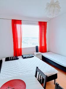 a bedroom with two beds and a window with red curtains at Aurora City Apartment in Rovaniemi