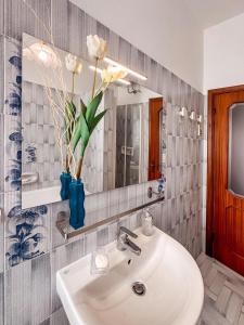 a bathroom with a sink and a mirror and a vase with flowers at [5 TERRE]The Terrace on the Gulf - Parking / Wi-fi in Lavagna