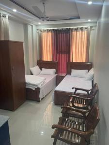 a bedroom with two beds and a chair in it at Independant Studio Flat in Faisal Town Islamabad. in Islamabad