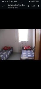2 Betten in einem kleinen Zimmer mit Fenster in der Unterkunft Villa Adamo in Santa Maria Del Focallo