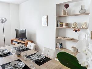 een eetkamer met een tafel en een televisie bij Le Lodge - Bleu lavande in Le Meux