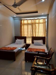 a bedroom with two beds and a chair and a window at Independant Studio Flat in Faisal Town Islamabad. in Islamabad