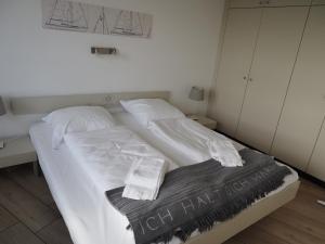 ein Bett mit weißer Bettwäsche und Kissen darauf in der Unterkunft Ferienwohnung Schleiverliebt 19-8 im Wikingturm Schleswig in Schleswig
