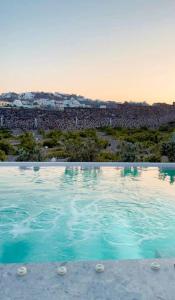 een zwembad met een stad op de achtergrond bij Vineyard Exclusive Suites in Akrotiri