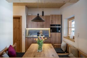 a kitchen with a wooden table with a vase of flowers on it at Kirchberg Chalet by Alpine Host Helpers in Kirchberg in Tirol