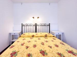 um quarto com uma cama amarela e duas mesas brancas em Casa Olivi Calmasino em Calmasino