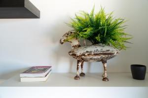 a plant in a vase on a table with a book at Sea View & Sundown, 150m from the Beach and Surf Spots in Costa da Caparica