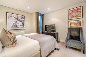 a bedroom with a bed and a chair and a television at Merchant Square Paddington in London