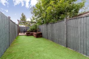 a backyard with a fence and green grass at The Harlesden Villas in London