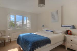 a white bedroom with a bed and a window at 2 Studley Gardens in Lyme Regis