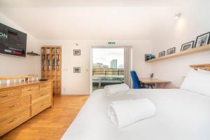 um quarto com uma grande cama branca e uma janela em Pass the Keys - Sunny flat with Great views over Canary Wharf, London em Londres