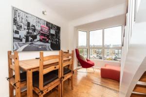 uma sala de jantar com uma mesa e uma cadeira vermelha em Pass the Keys - Sunny flat with Great views over Canary Wharf, London em Londres