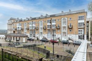 a large brick building with cars parked in front of it at Pass the Keys - Sunny flat with Great views over Canary Wharf, London in London