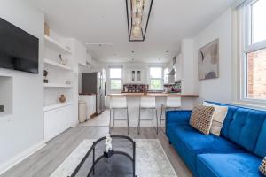 a living room with a blue couch and a kitchen at The Harlesden Villas in London