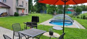 un patio con mesa, sombrilla y piscina en Apartmán u Toma, en Frýdlant nad Ostravicí