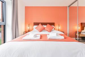 a bedroom with a large bed with orange walls at Smart 1 Bed Apartment Nightingale Quarter Derby in Derby