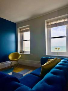 a living room with a blue couch and two windows at Beach Haven Apartment By Air Premier in Seaford
