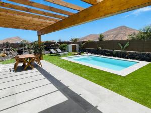 einen Pool im Garten mit einem Tisch und einem Picknicktisch in der Unterkunft Bungalow + Piscina independiente in La Oliva
