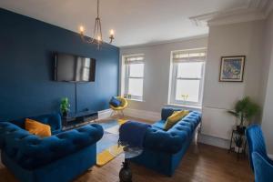 a living room with blue couches and a tv at Beach Haven Apartment By Air Premier in Seaford