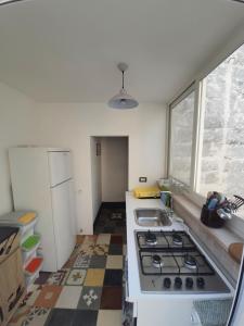 Una cocina con estufa, fregadero y ventana. en Casa Ginevra, en Monopoli