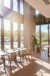 a dining room with tables and chairs and windows at Atenea Living in Mataró