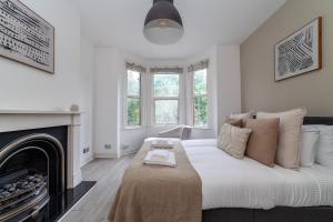 um quarto branco com uma cama e uma lareira em The Harlesden Villas em Londres