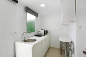 La salle de bains blanche est pourvue d'un lavabo et d'une fenêtre. dans l'établissement Atico vecindario, aeropuerto, à Cruce de Arinaga