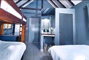een slaapkamer met 2 bedden en een bureau met een spiegel bij Ndalo Lodge Mbombela in Nelspruit