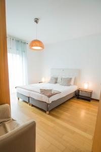 um quarto branco com uma cama e um sofá em Casas e Quintas de Praia em Praia da Barra