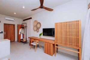 a room with a desk with a tv and a ceiling fan at Samawa Living in Paje