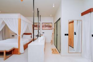a bedroom with a canopy bed and a bathroom at Samawa Living in Paje