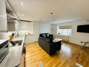 a living room with a black couch and a kitchen at West Street Mews - Serviced Accommodation in Exeter