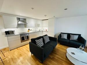 a living room with two couches and a kitchen at West Street Mews - Serviced Accommodation in Exeter