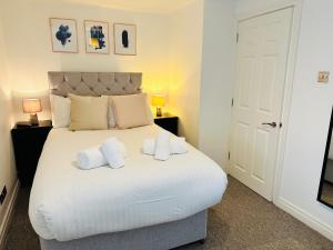 a bedroom with a large white bed with towels on it at West Street Mews - Serviced Accommodation in Exeter