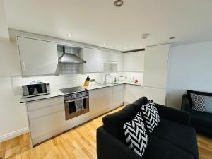 a kitchen with white cabinets and a black couch at West Street Mews - Serviced Accommodation in Exeter