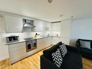a kitchen with white cabinets and a black couch at West Street Mews - Serviced Accommodation in Exeter