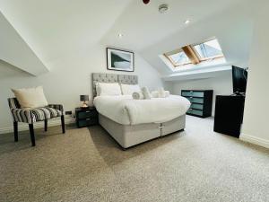 a bedroom with a large bed and a chair at West Street Mews - Serviced Accommodation in Exeter