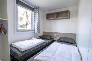 Duas camas num quarto com uma janela em Mobilhome au bois masson em Saint-Jean-de-Monts