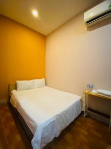 - une chambre avec un lit blanc et un mur jaune dans l'établissement Tokyo Homestay, à Hô-Chi-Minh-Ville