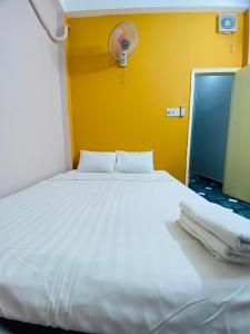 - un lit blanc dans une chambre dotée d'un mur jaune dans l'établissement Tokyo Homestay, à Hô-Chi-Minh-Ville