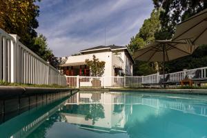 a swimming pool with a white fence and an umbrella at Hyde Park Guest House in Johannesburg