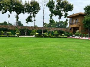 a large green yard with a building in the background at Krishna Vatika Hotel in Shivāpur