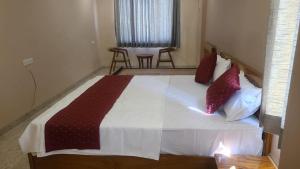 una camera da letto con un grande letto con cuscini rossi e bianchi di Krishna Vatika Hotel a Shivāpur