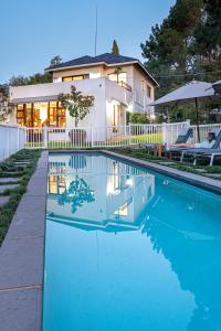 uma casa com piscina em frente a uma casa em Hyde Park Guest House em Joanesburgo