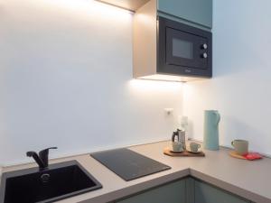 a kitchen with a sink and a microwave at Renovated studio apartment - Navigli area in Milan