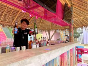 Slumber Resort Koh Chang في ترات: امرأة تقف عند بار مع زجاجتين من البيرة
