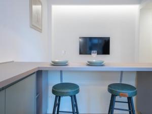 a bar with two stools at a counter with a tv at Renovated studio apartment - Navigli area in Milan