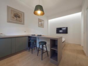 a kitchen with a bar with stools and a tv at Renovated studio apartment - Navigli area in Milan