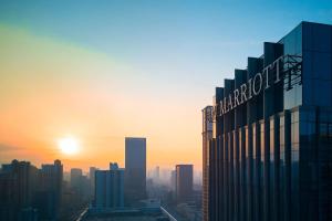 a city skyline with the sun setting behind a building at JW Marriott Hotel Taiyuan in Taiyuan
