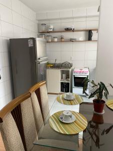 a kitchen with a table and chairs and a refrigerator at Apartamento aconchegante em Betim in Betim